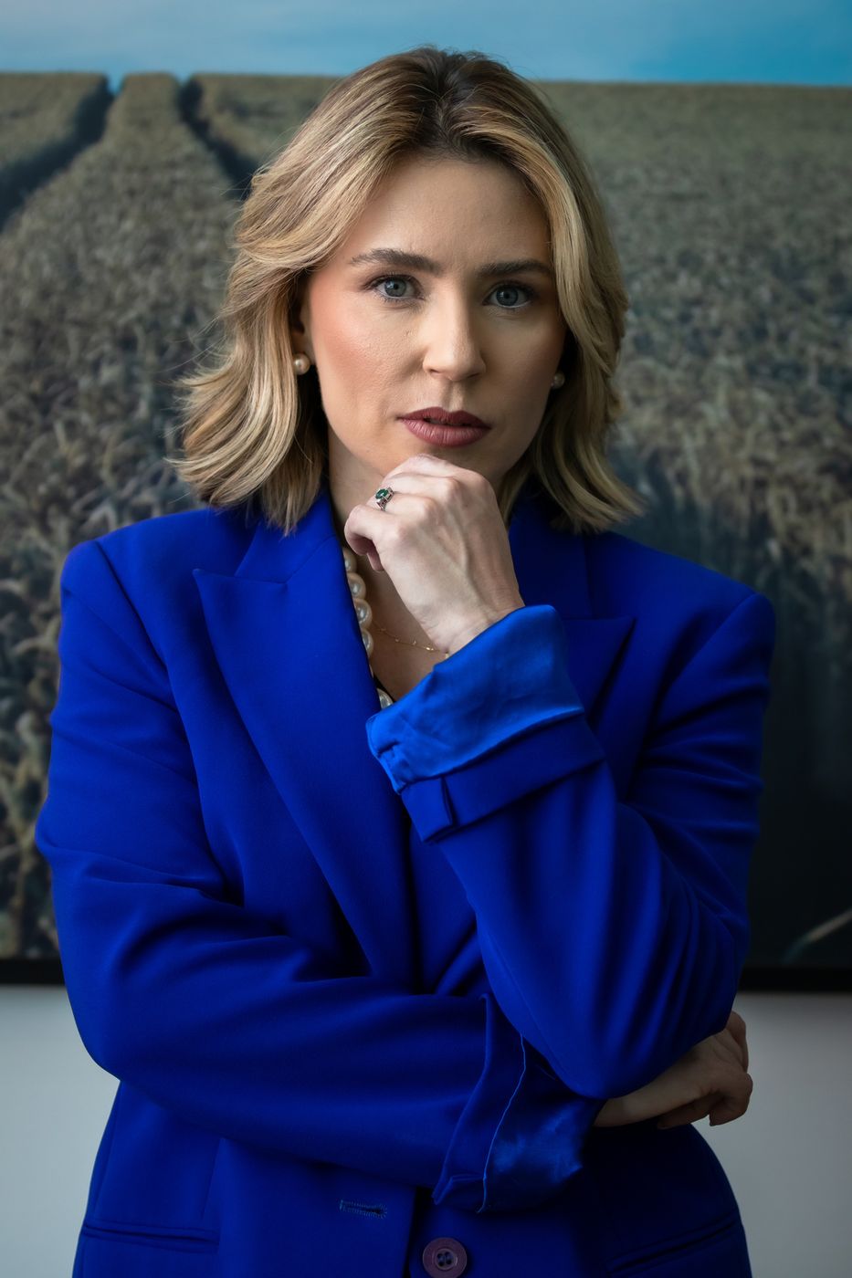 Pauliane Oliveira, de blazer azul, diante de uma lavoura