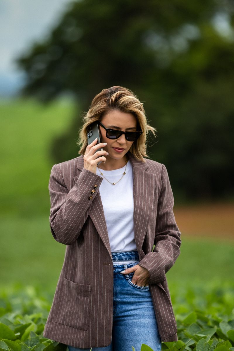 Pauliane Oliveira ao telefone, em meio a uma lavoura de soja
